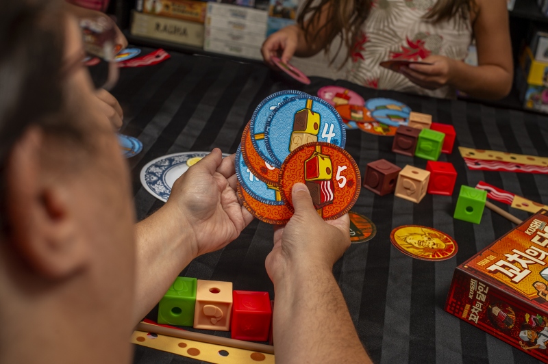 A closeup of a family playing the board game Kushi Express from Mandoo Games.